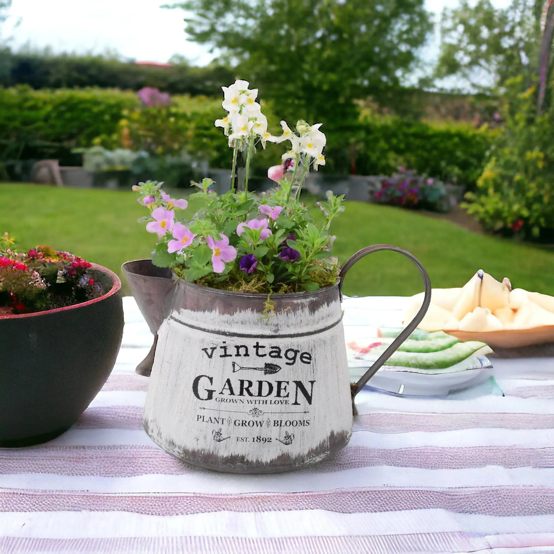 Rustic vintage jug planter filled with summer flowers including bacopa, nemesia, and calibrachoa, displayed on an outdoor garden table.